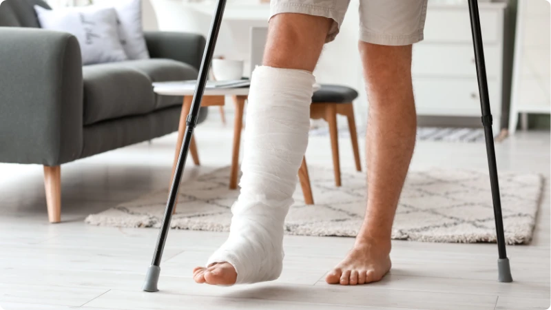 Pessoa com perna engessada e muletas em casa. Post: Osteoporose: prevenção e fortalecimento ósseo