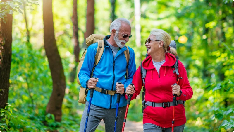 10 Dicas Essenciais para um Envelhecimento Saudável. Casal idoso fazendo caminha na floresta.