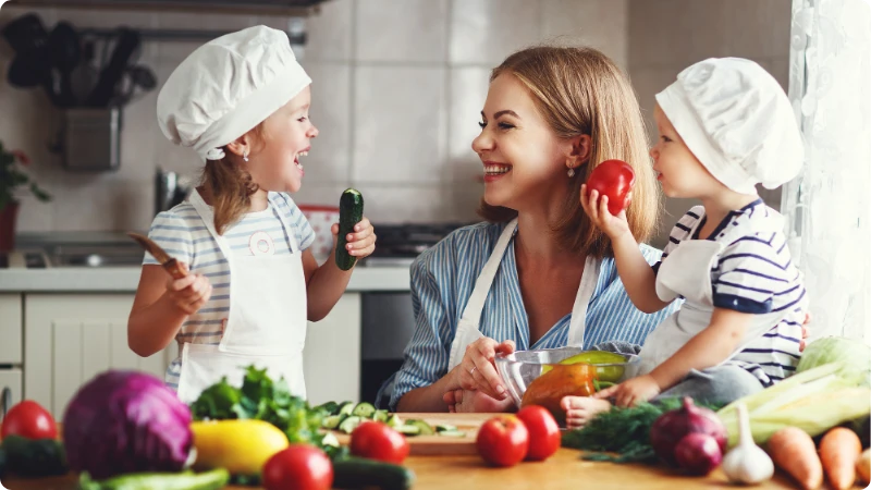 Os benefícios da alimentação saudável. Mãe de família feliz e crianças preparando salada de legumes.