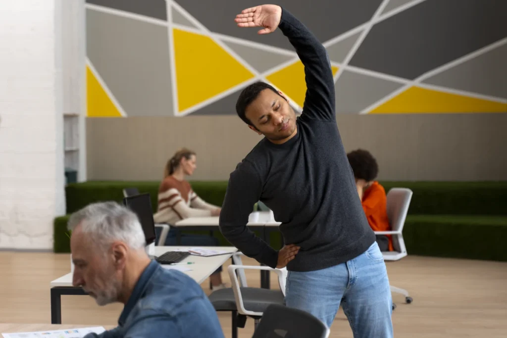 7 Benefícios do Alongamento: Seu Corpo Vai Agradecer. Homem no escritório se alongando durante um dia de trabalho.