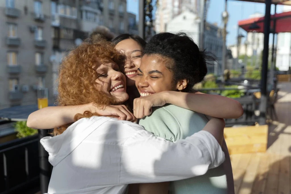 Saúde Preventiva: O Que É, Qual Sua Importância e Benefícios. Três amigas, mulheres jovens, felizes se abraçando.