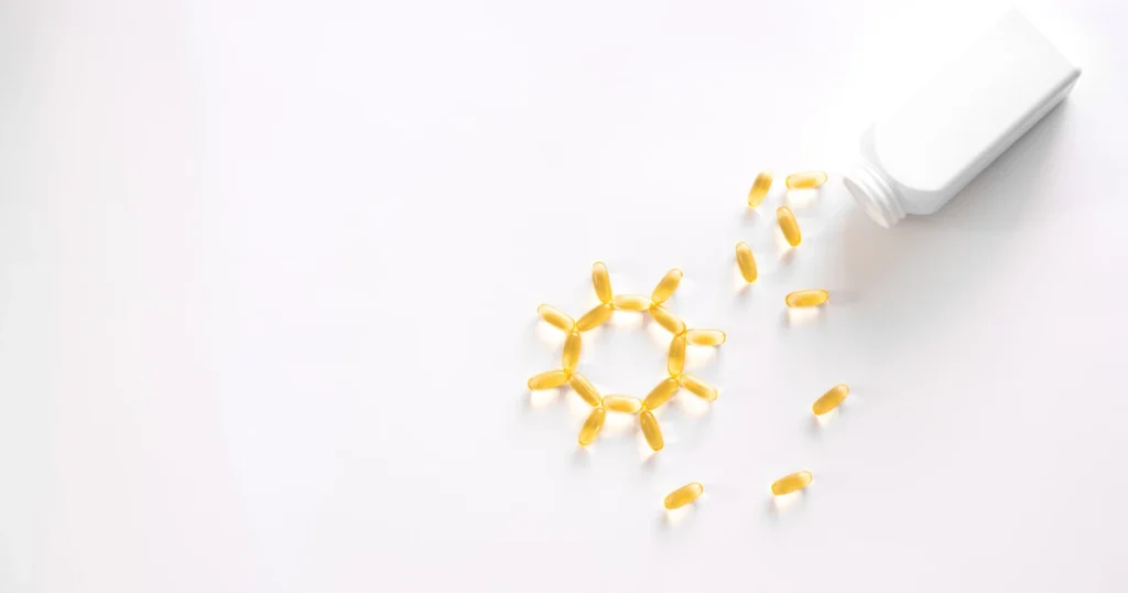 Vitamina D: o que é, benefícios, como obter e medir. Cápsulas de vitamina D em um plano de fundo branco.