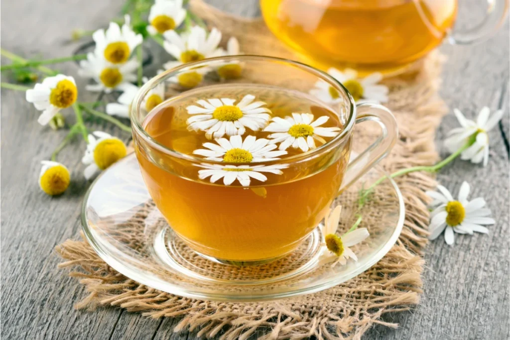 Camomila: o que é, para que serve, benefícios e como usar. Uma xícara com chá de camomila e flores da planta.