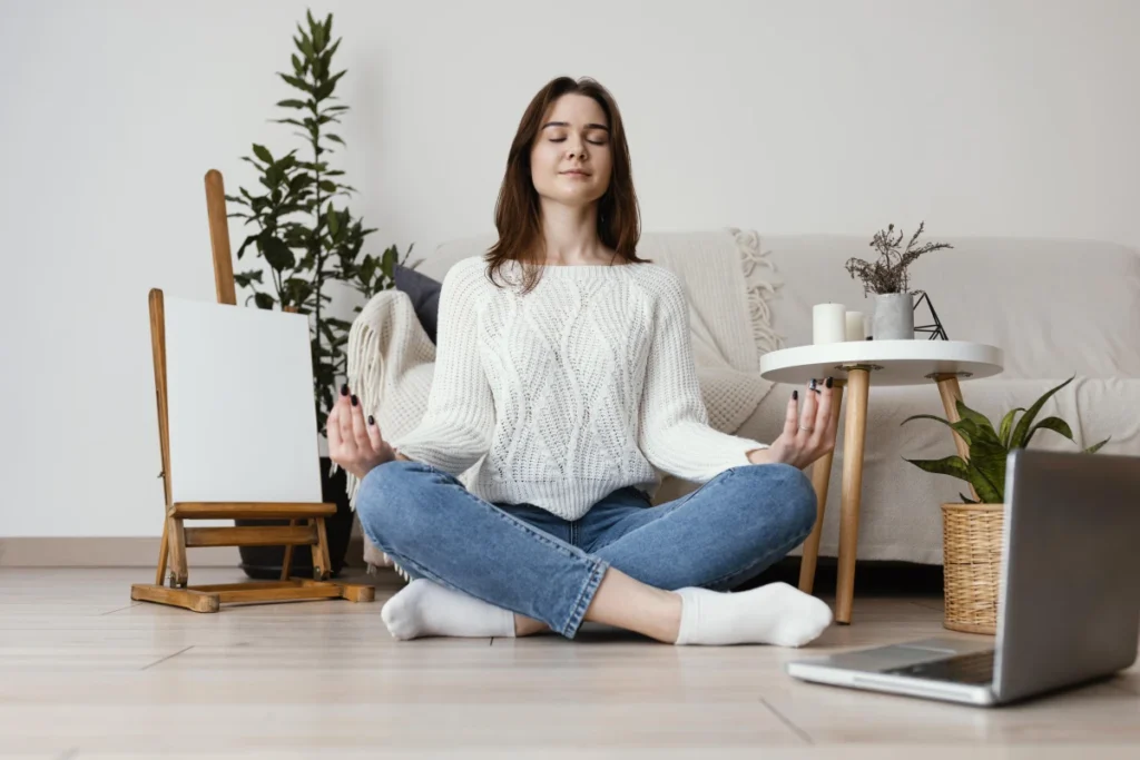 Cansaço Mental: Como Identificar, Entender e Combater a Exaustão da Mente. Uma jovem mulher meditando na sala de casa.