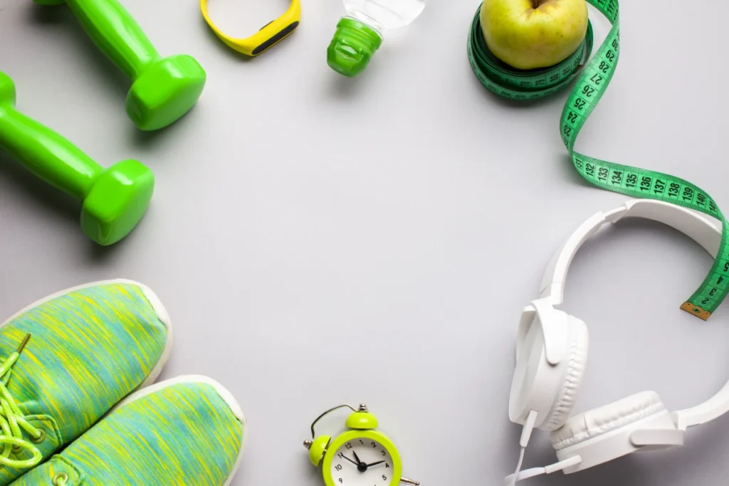 Chá de Salsa Emagrece? 7 Benefícios e Como Preparar. Vista superior equipamento para prática de atividade física, um par de tênis, halteres, relógios, fita métrica, fone de ouvido, garrafinha de água e uma maçã.