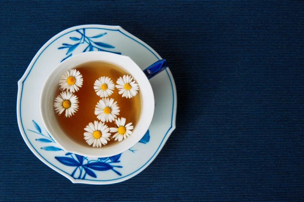 Chás para Dormir: 7 Melhores Opções Naturais e Como Fazer. Chá de camomila em uma xícara em um fundo escuro.