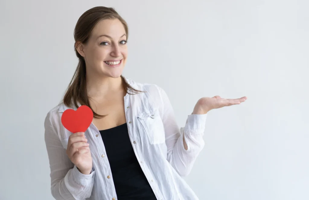Dieta Mediterrânea: O Que é, Benefícios e Como Fazer. Mulher bonita sorridente segurando coração de papel.