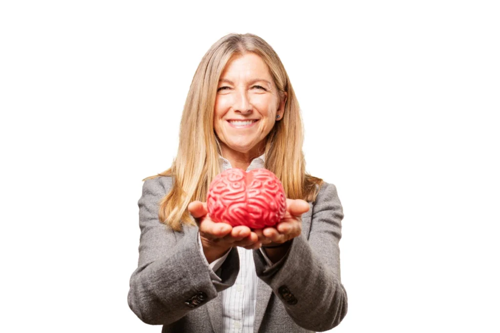 Dieta Mediterrânea: O Que é, Benefícios e Como Fazer. Mulher madura, sorridente, apresentando um protótipo de cérebro humano com as duas mãos.
