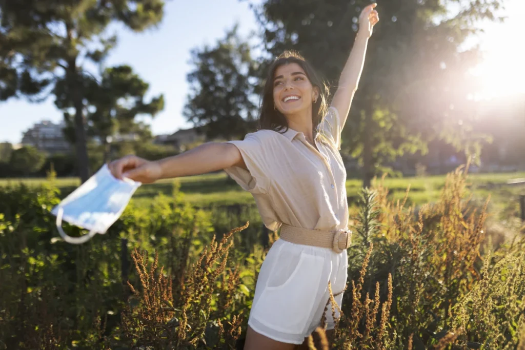 Doenças Respiratórias no Inverno Como Prevenir. Mulher sorridente em um jardim, ostentando saúde e se sentindo livre das mascaras.