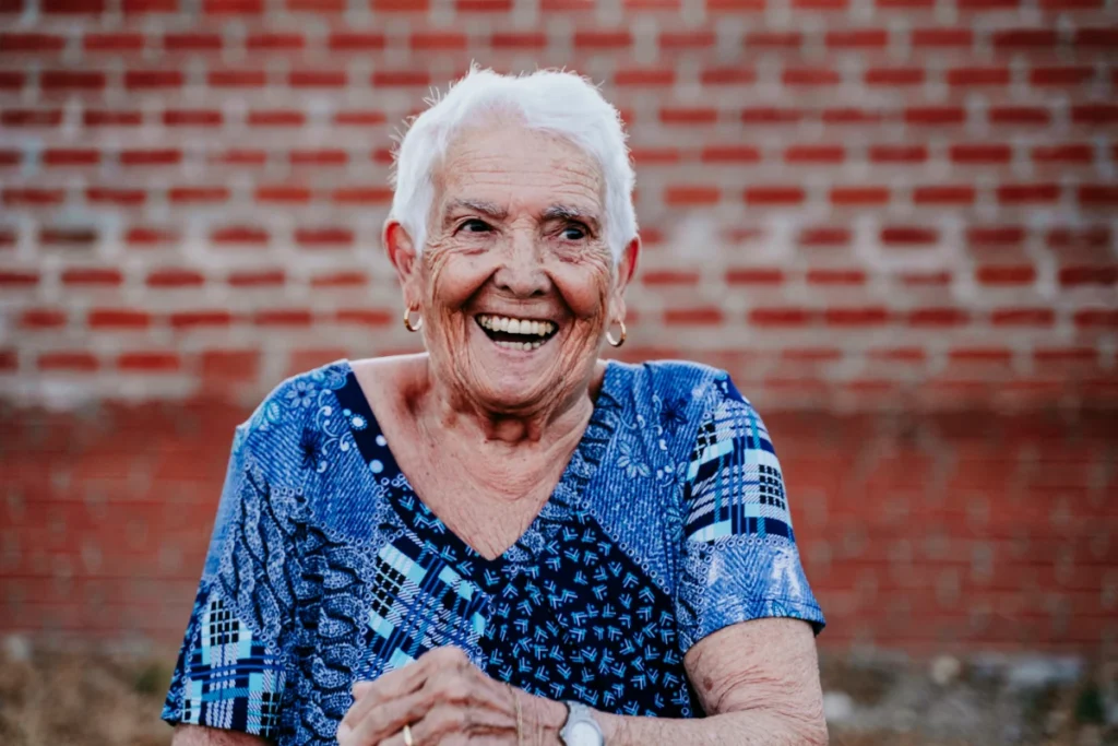 Idoso Feliz: Como Ter Alegria e Bem-Estar com 8 Dicas. Idosa muito alegre sorrindo.
