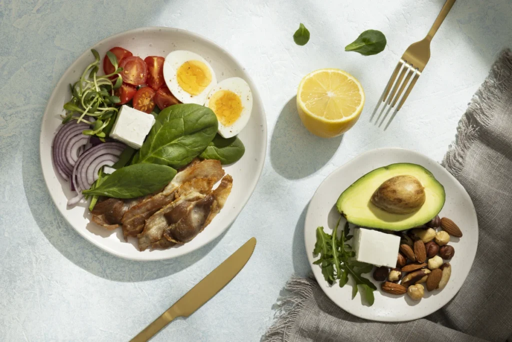 O Que Comer à Noite Para Não Engordar. Uma refeição saudável sobre a mesa em dois pratos com ovos, vegetais frescos, cereais, abacate, laranja, queijo, frango.