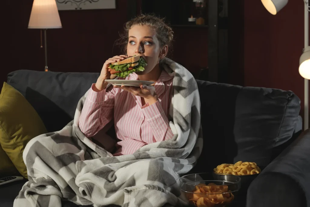 O Que Comer à Noite Para Não Engordar. Mulher jovem e bonita comendo alimentos não saudáveis à noite.