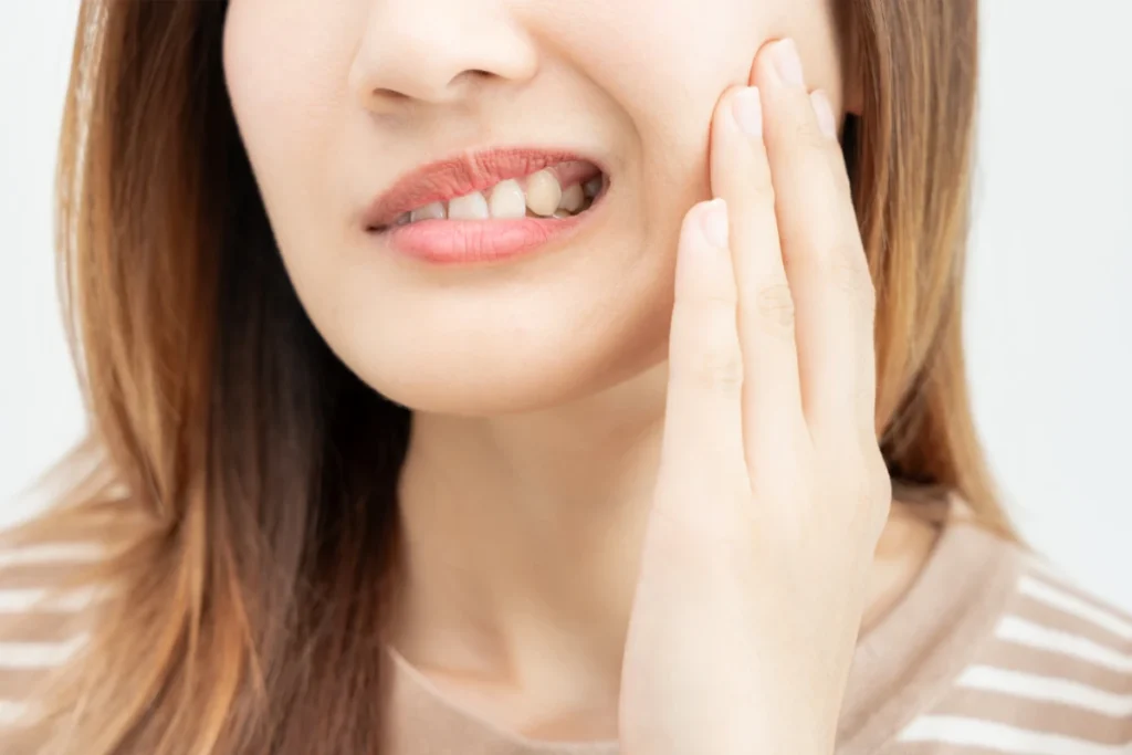 Refrigerante Faz Mal? Descubra a Verdade e Proteja Sua Saúde. Mulher com a mão no rosto sentindo dor de dente.