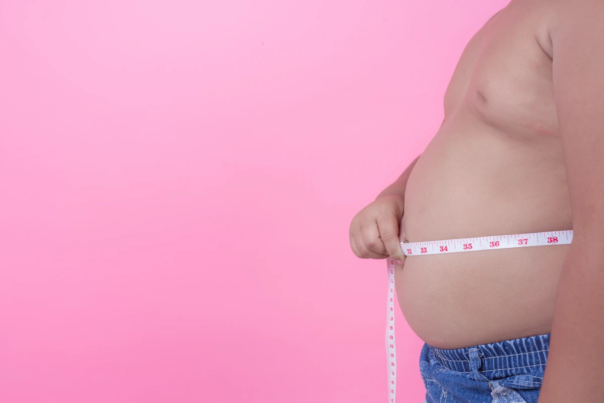 Sobrepeso e Obesidade: Diferenças, Causas e Como Identificar. Homem jovem obeso que está acima do peso em um fundo rosa.