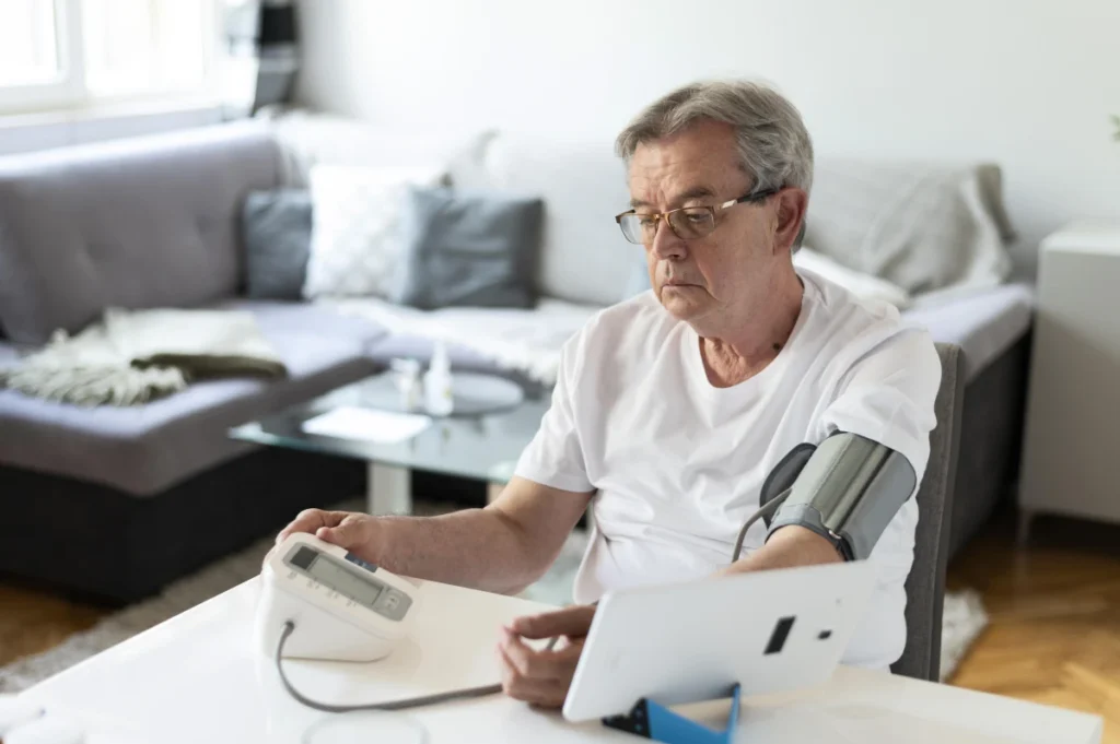 Telemedicina para Idosos: Benefícios e Como Funciona. Um homem idoso medindo a pressão arterial em consulta médica virtual.