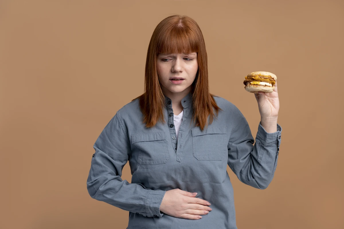 Mulher segurando a barriga com expressão de desconforto, destacando a importância de comer devagar para a digestão