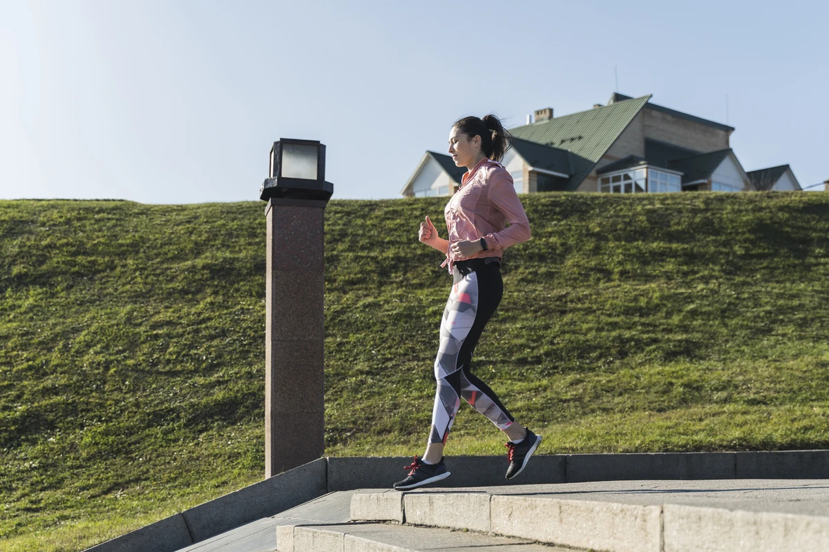 Jovem mulher correndo em parque demonstrando como potencializar a caminhada para emagrecer com exercício aeróbico