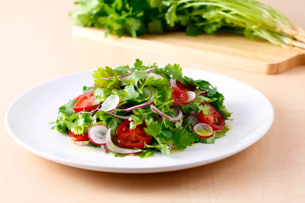 A Erva Que Divide Opiniões Mas Pode Reduzir o Açúcar no Sangue. Um prato sobre a mesa com uma salada de coentro fresco.