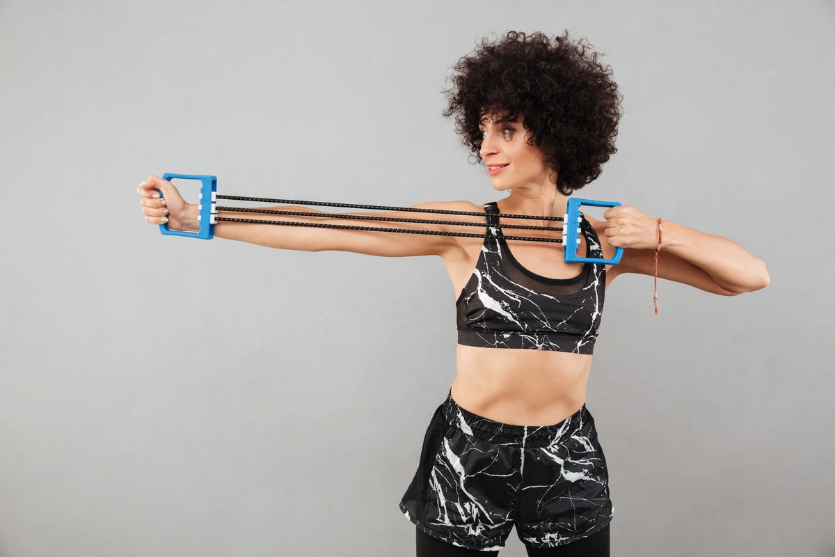 Jovem mulher realizando treino de força com expansor de mão em vista lateral