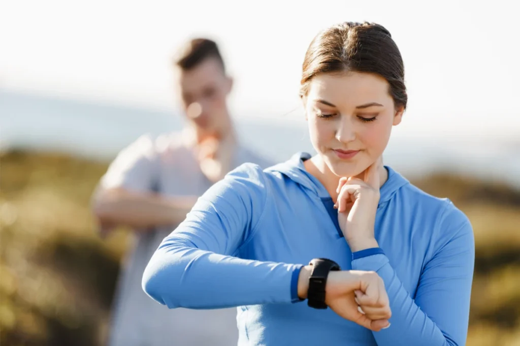 Como Calcular Sua Frequência Cardíaca Máxima. Mulher corredora monitorando a frequência cardíaca.